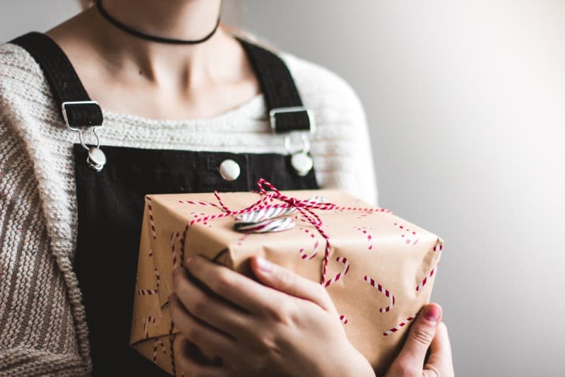 woman holding a present_featured image for the best travel gifts for mom article