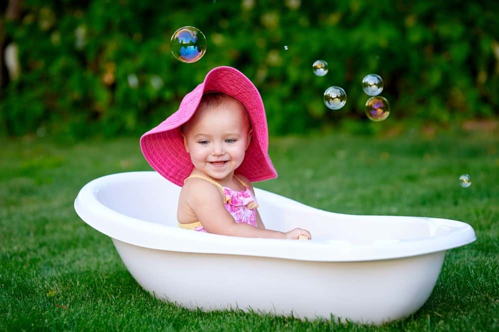 child with pink hat is playing in the best travel baby bath