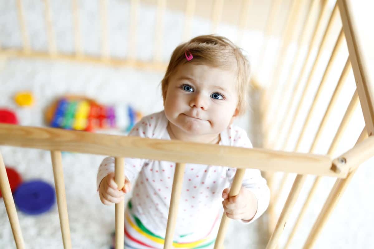 small baby standing in their baby travel playpen