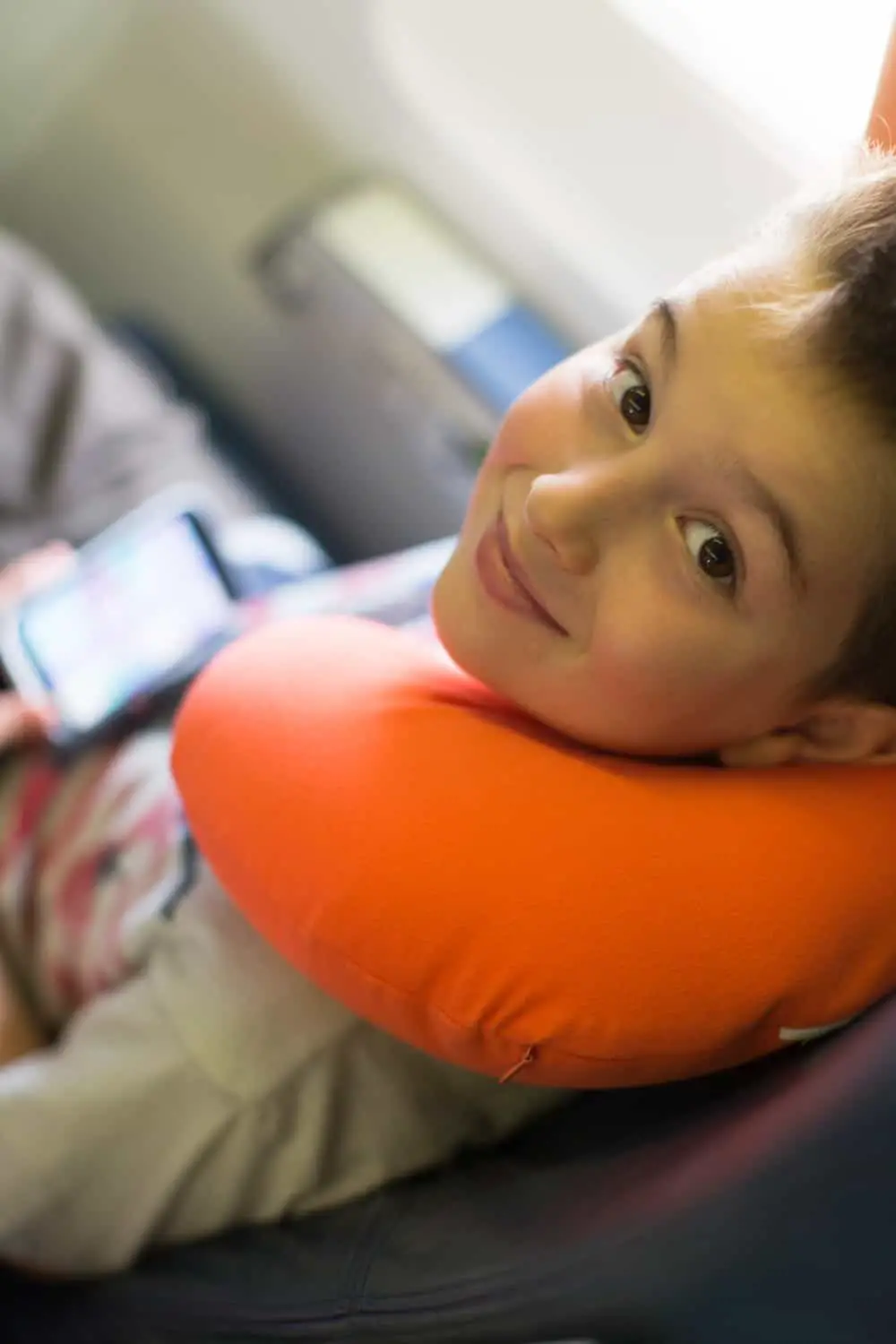 boy with an orange example of the best kids travel pillows