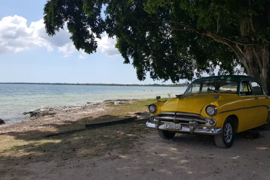 yellow vintage car on the beach, Playa Larga, Cuba, one of the best beaches in Cuba