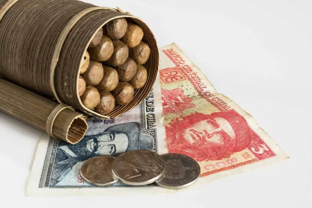 notes and coins of cuban pesos and a box of cigars for the trip to cuba cost article