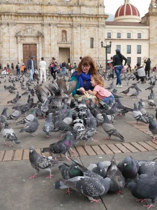 Family feeding birds in Plaza Mayor in Bogota