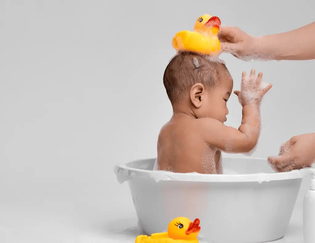 Photo of a baby in a best travel baby bath tub with duck toys above its head and below him.