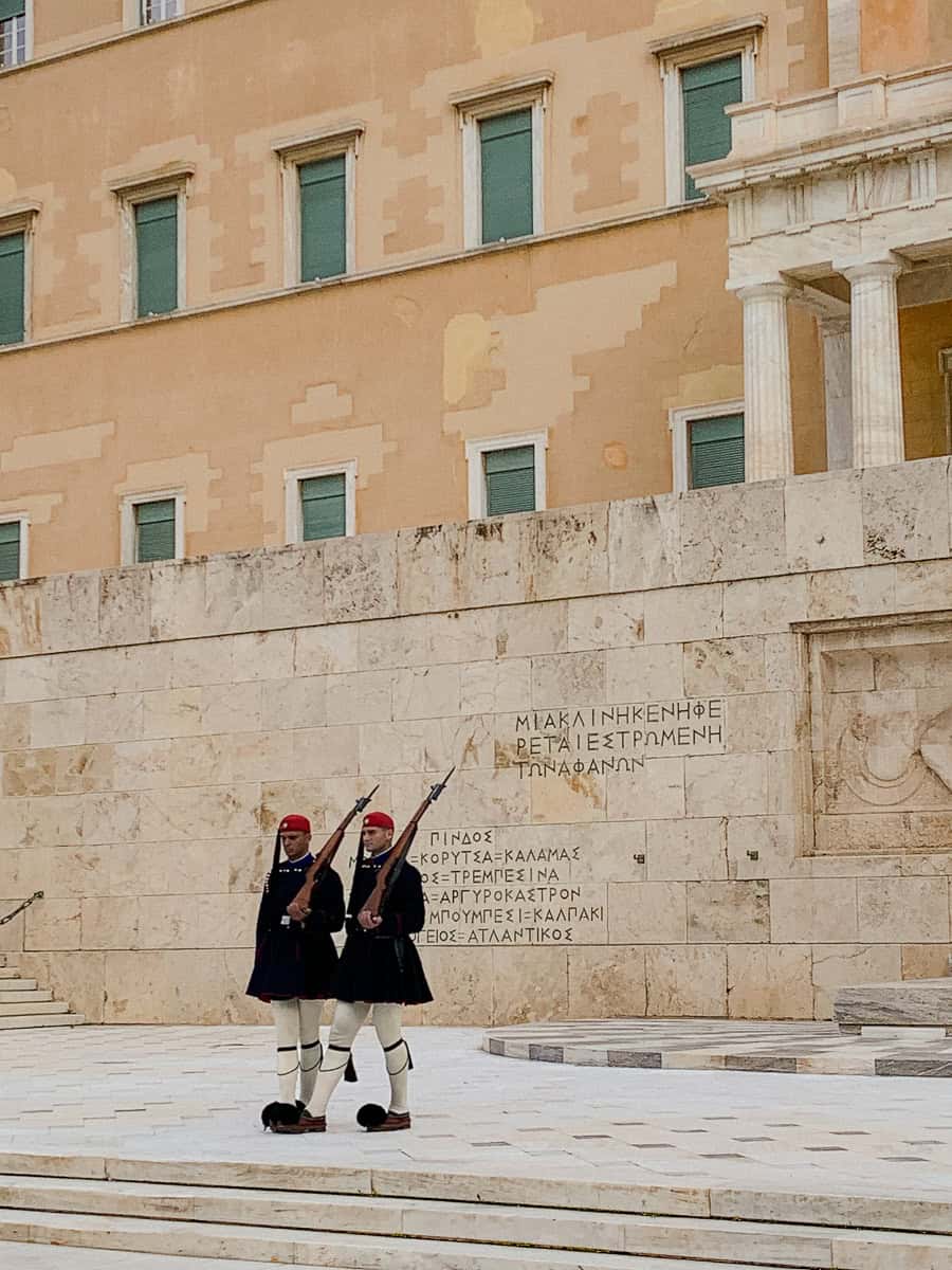 2 evzones standing still in front of the monument of the unknown soldier.