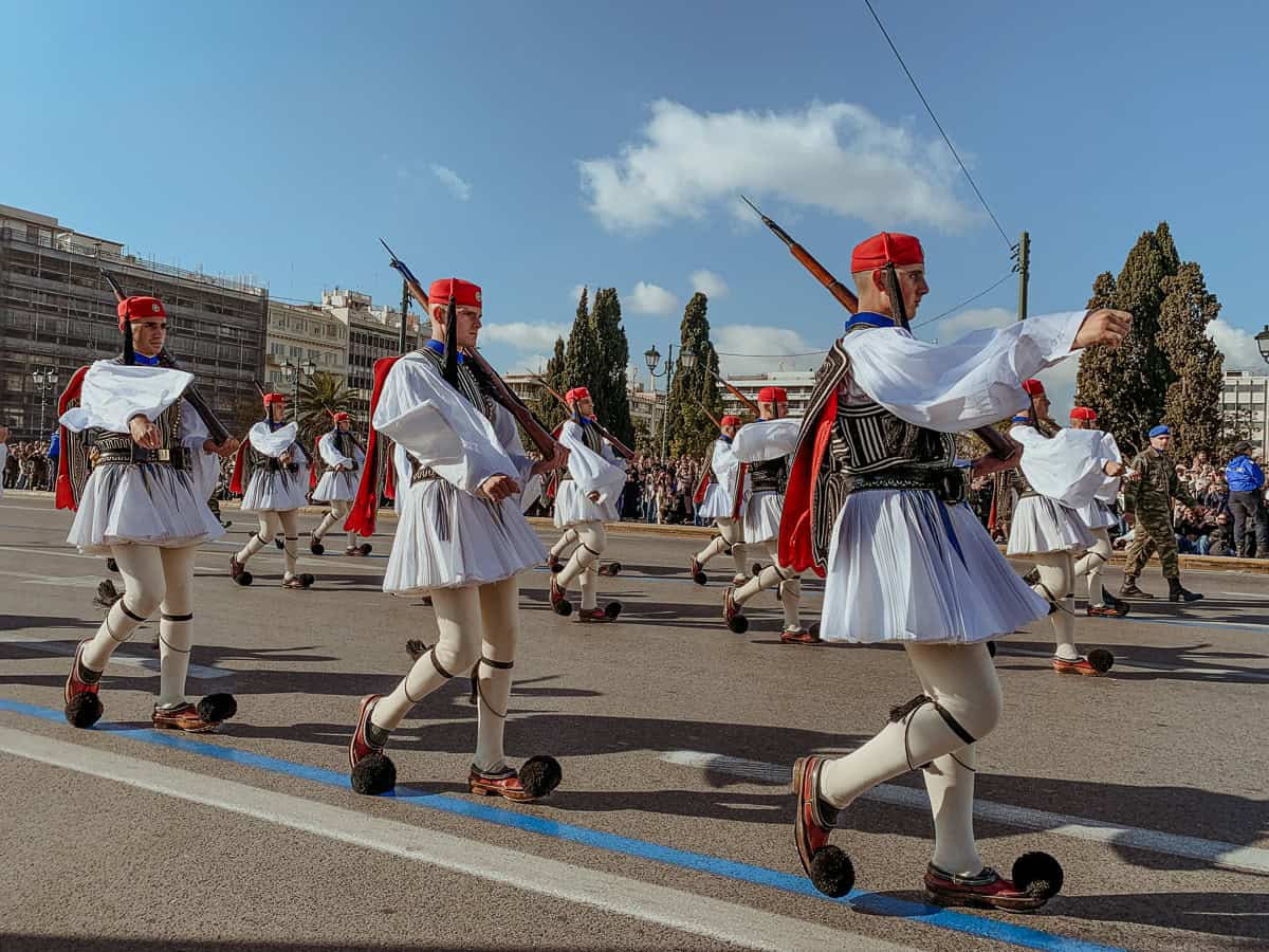 Evzones marching by in their traditional outfits.