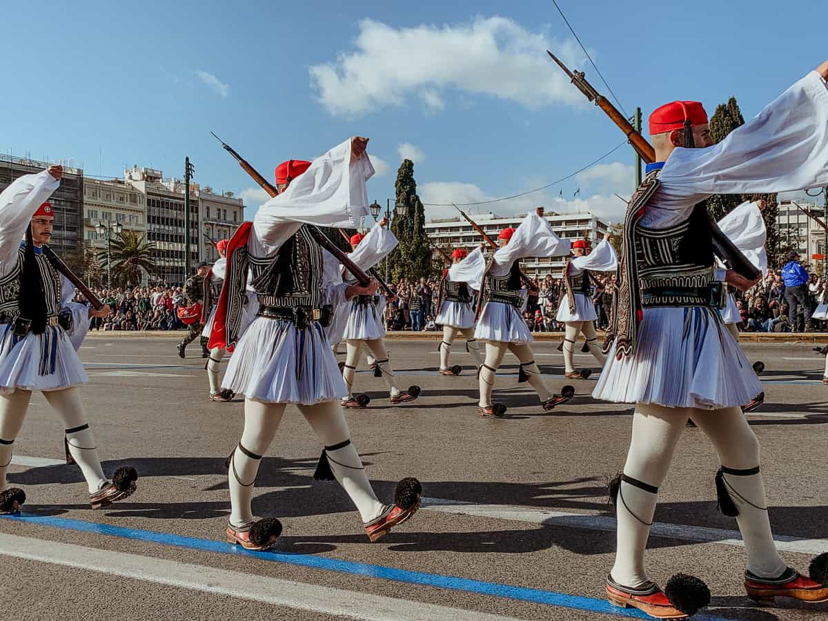 Evzones marching by in their traditional outfits.