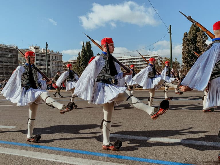 Evzones marching by in their traditional outfits.