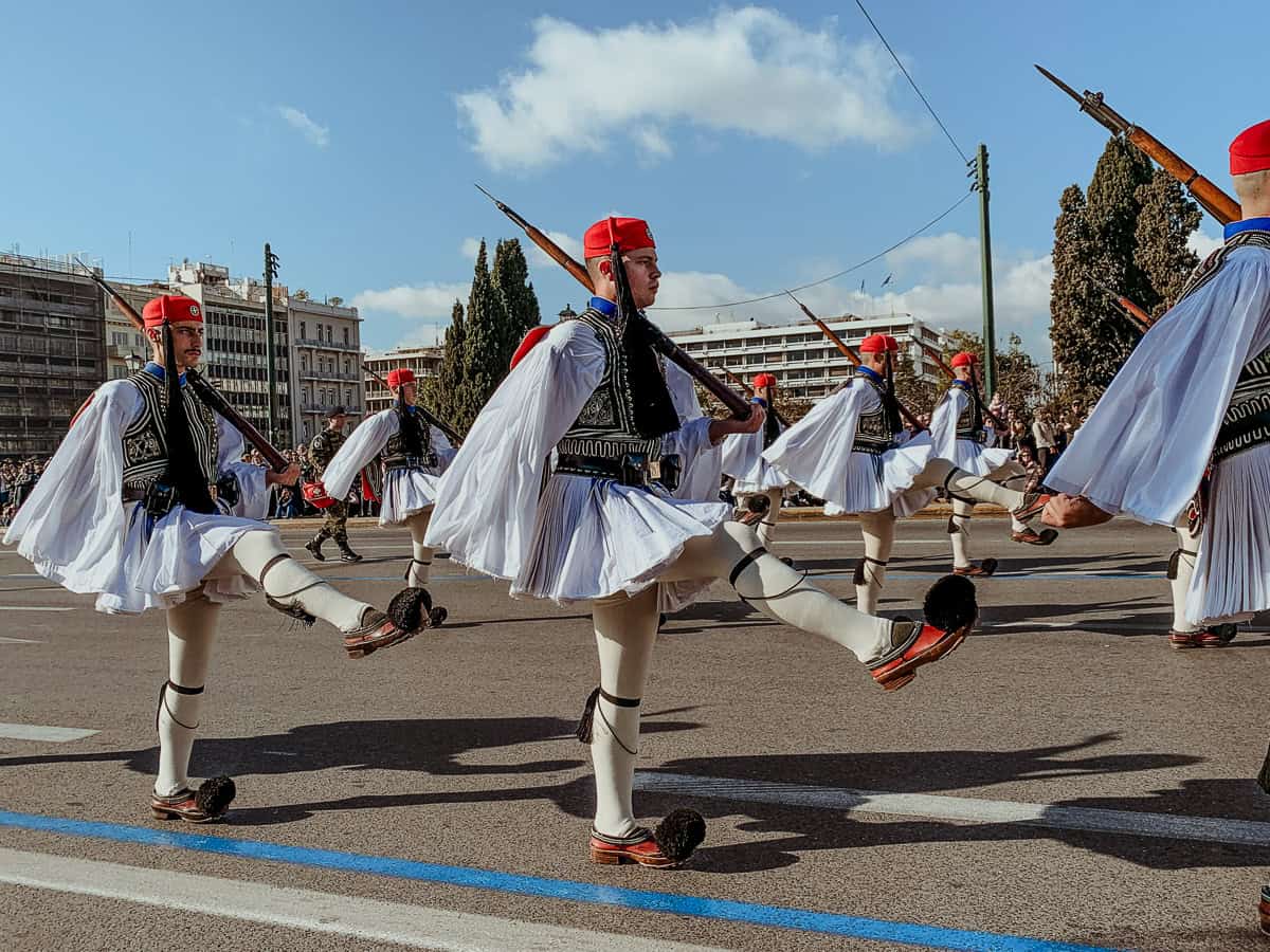Evzones marching by in their traditional outfits.