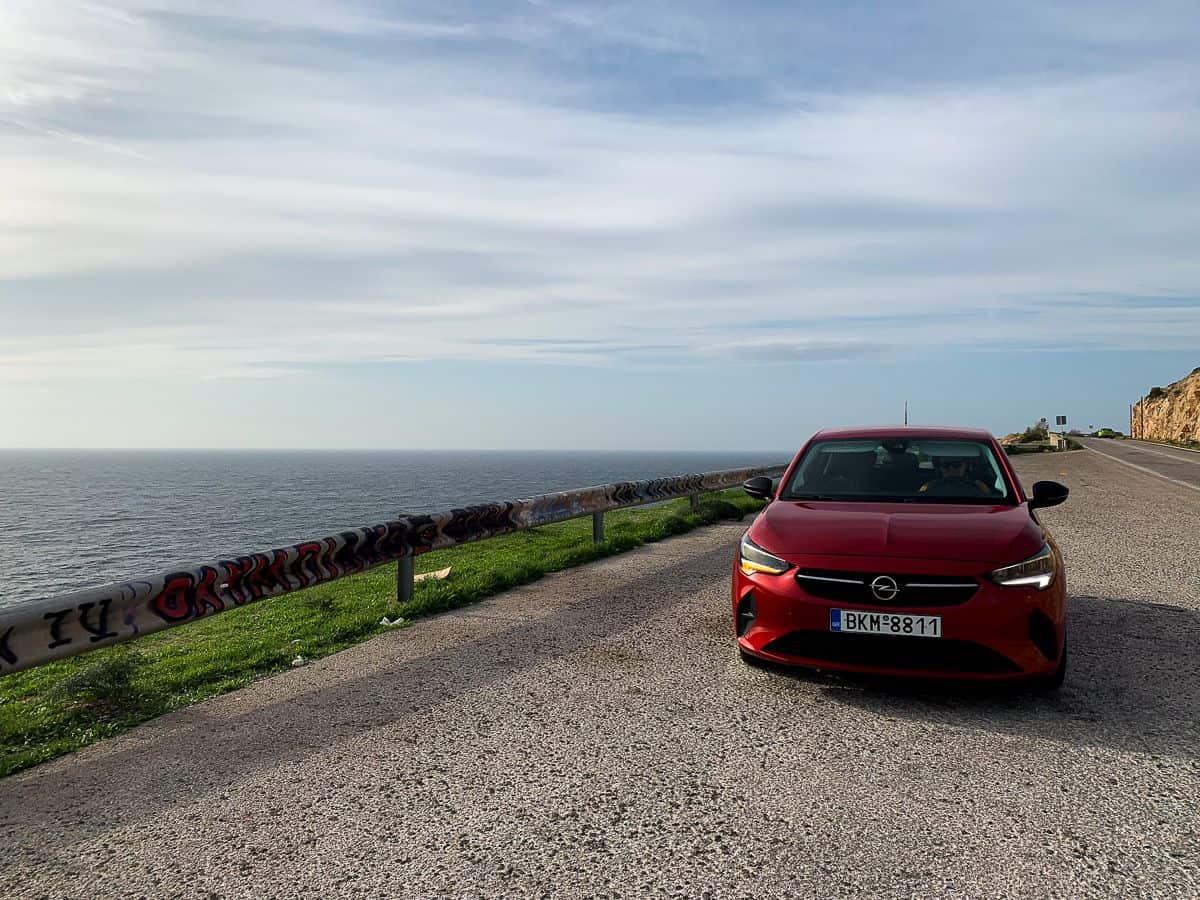 A red car parked near the edge of the cliff.