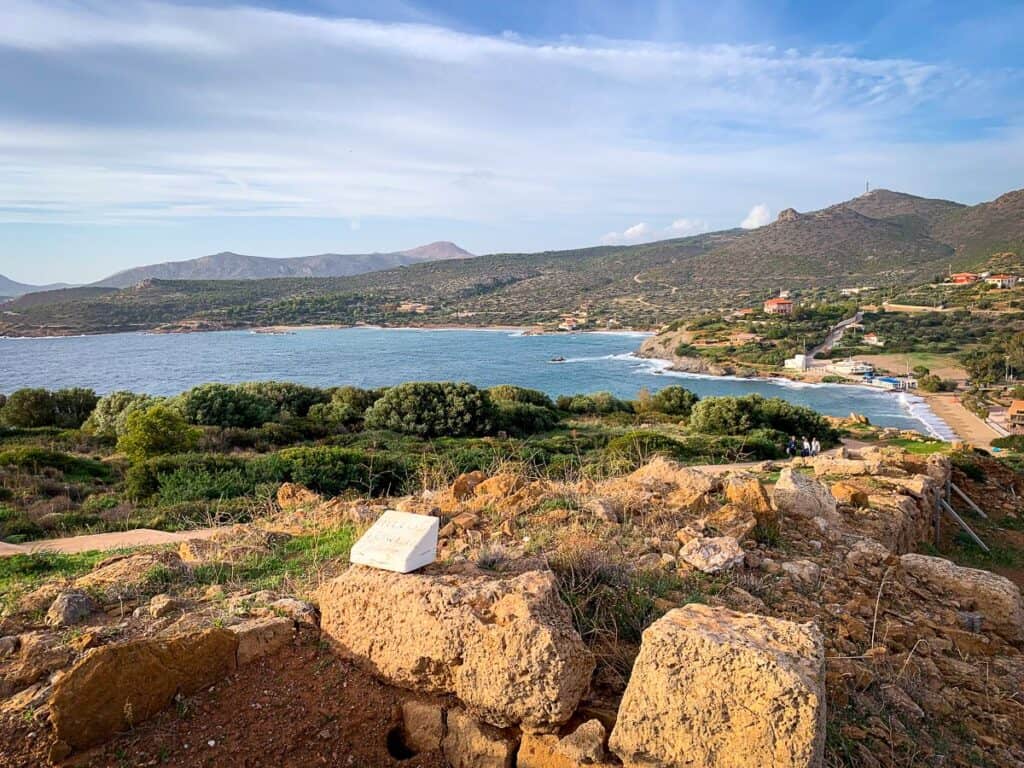 Rocky area with huge boulders and the view of the blue seas under a cloudy sky.