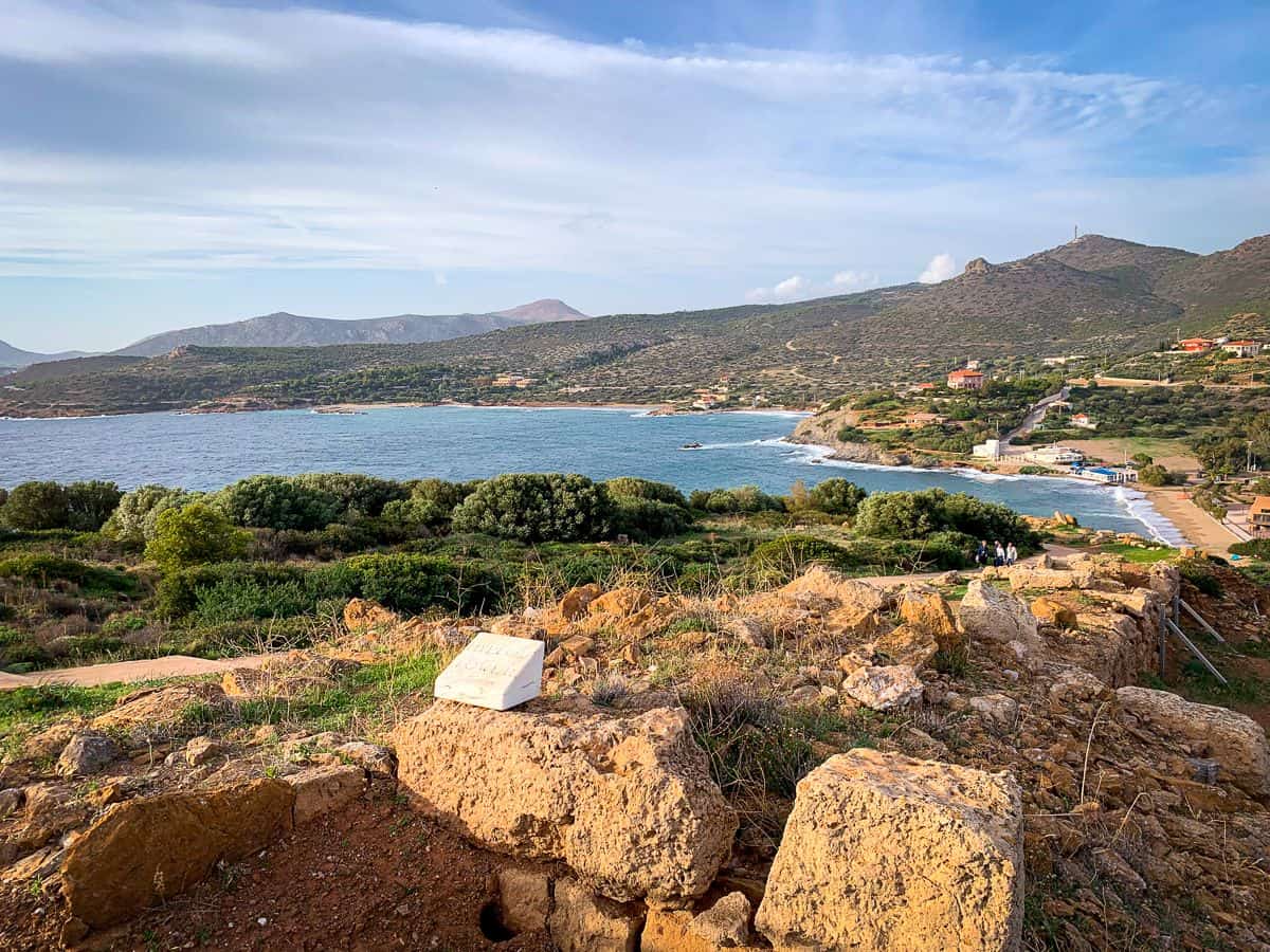 Rocky area with huge boulders and the view of the blue seas under a cloudy sky.