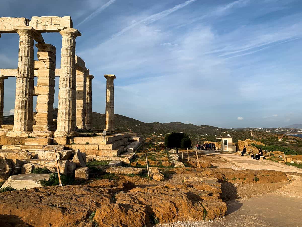 The Temple of Poseidon as the sun rays hit the columns and the boulders nearby.