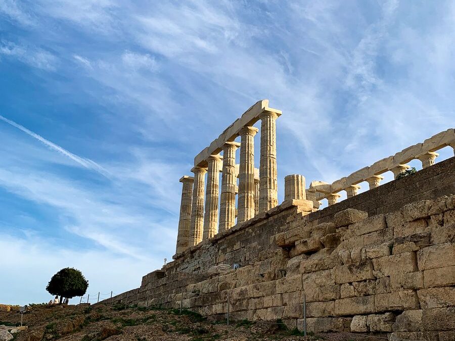 The pillars and walls of the Temple of Poseidon with a nearby tree.