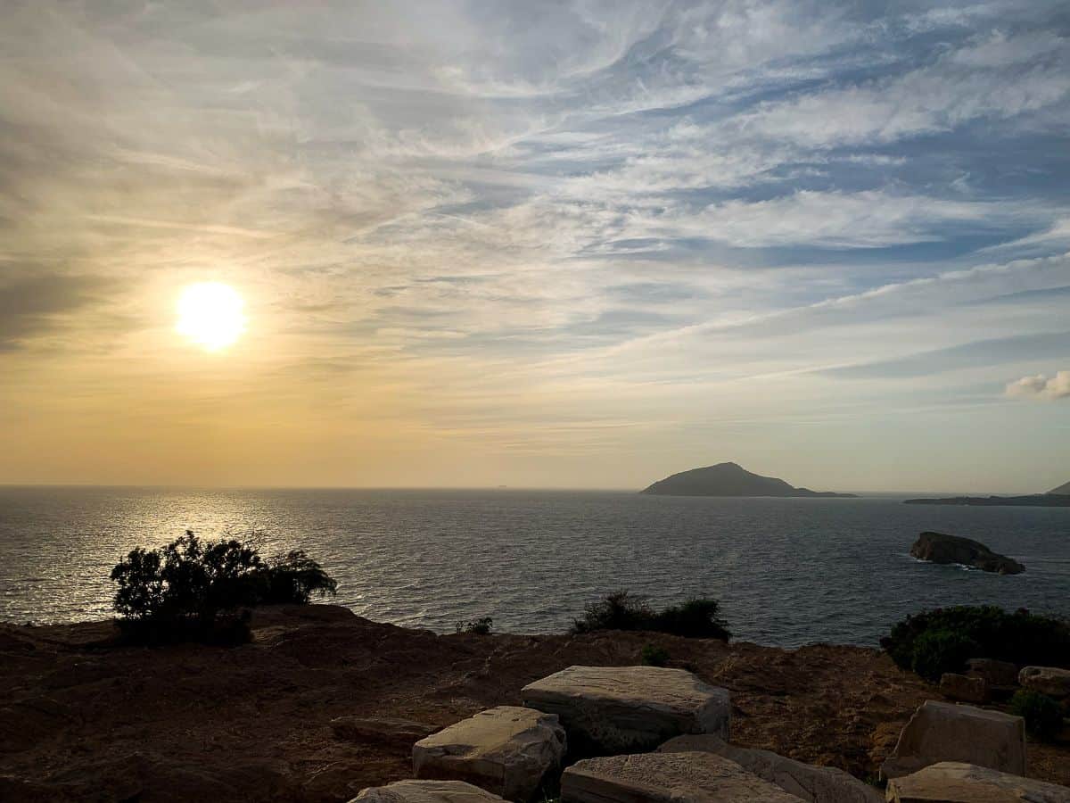 Temple of Poseidon in Greece on a sunset with an island nearby.