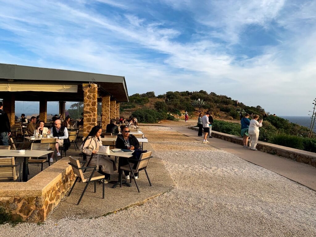 Benches filled with people in an area near the Temple of Poseidon.