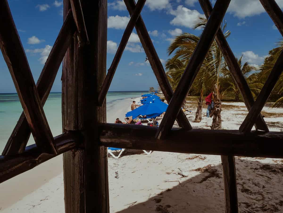 Beach view from inside a restaurant, with tourists visible in the lounging area.