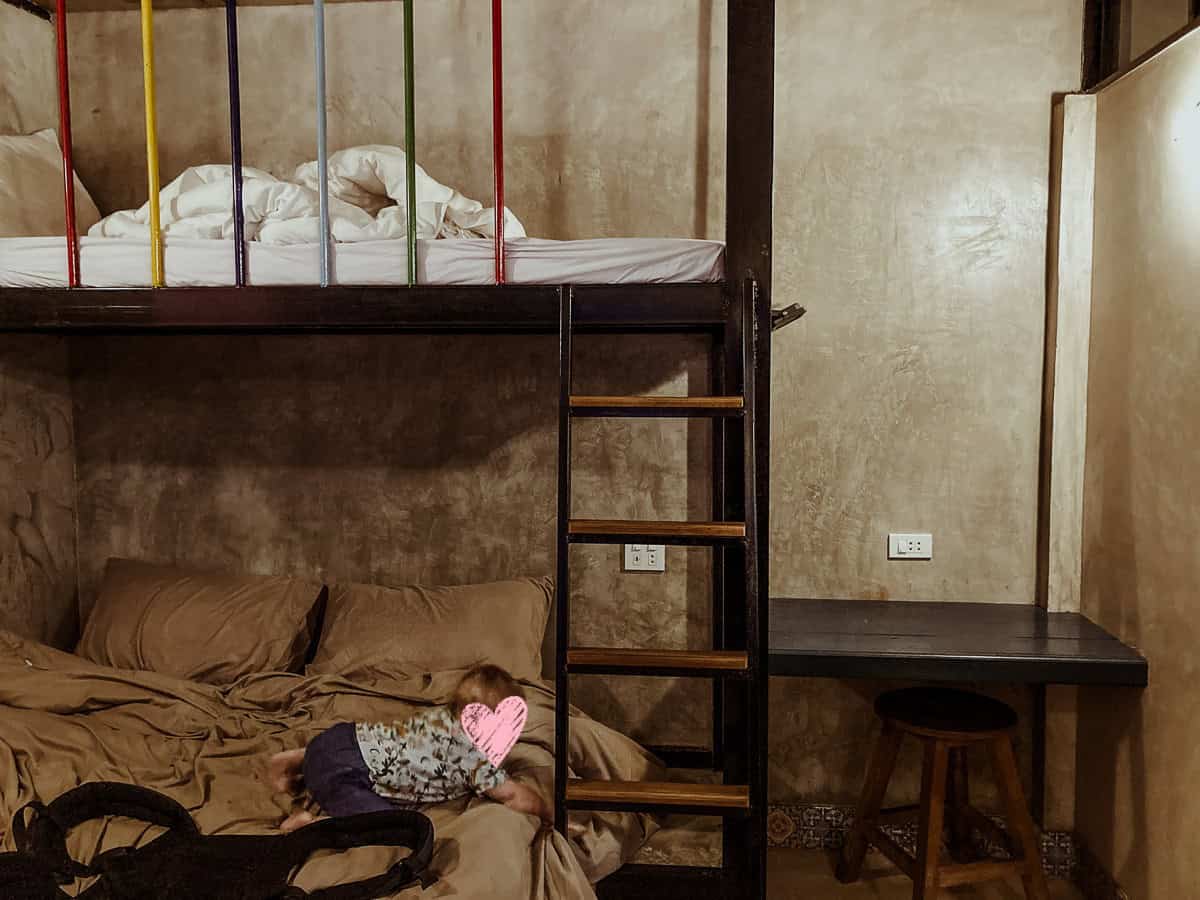 Oscar is playing on the bottom level of a sturdy, industrial-style bunk bed against a textured concrete wall.