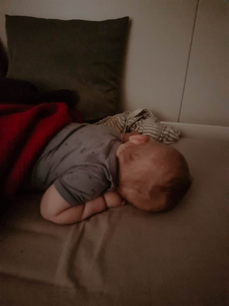 Baby sleeping peacefully on a hotel bed with pillows, during a family trip.