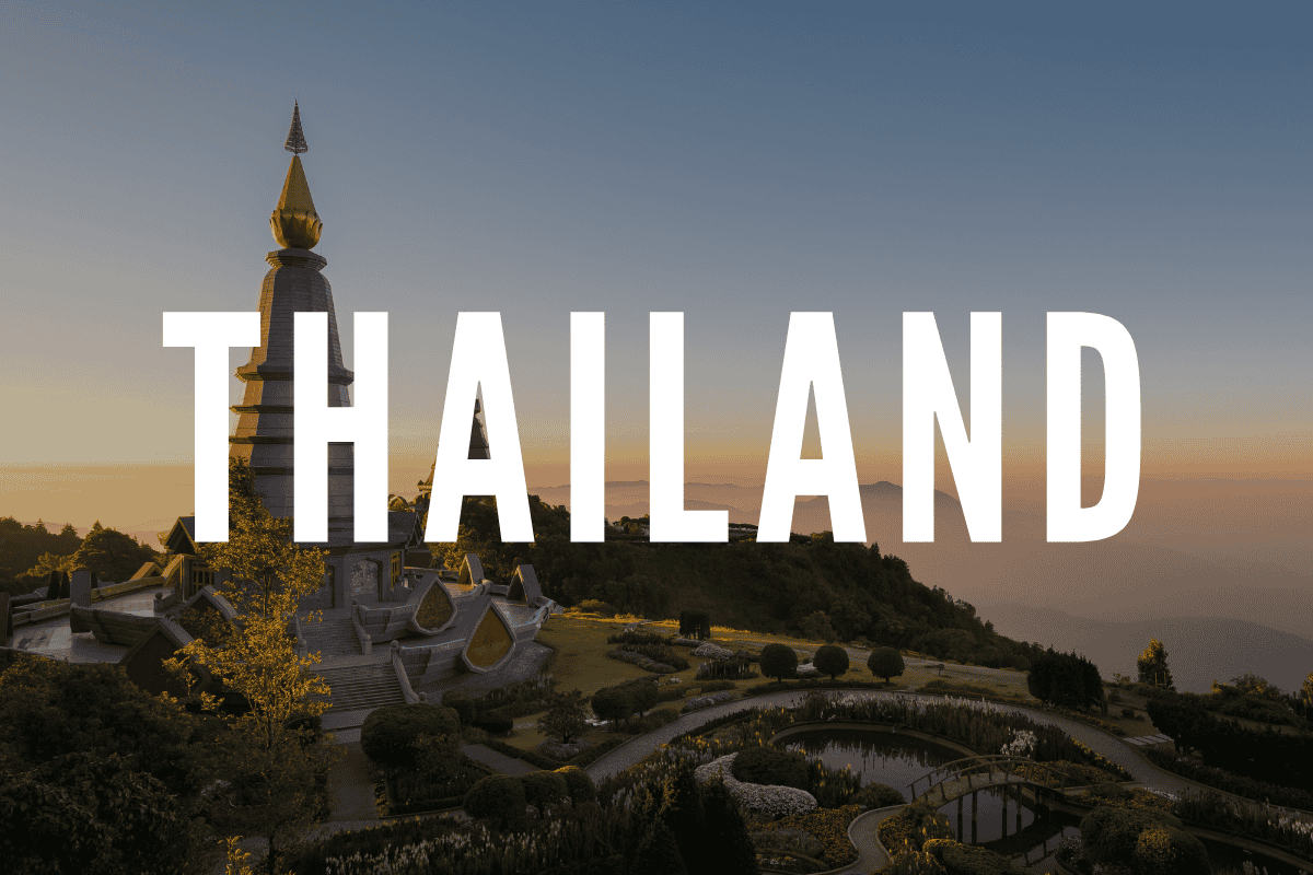 Thailand temple silhouette at sunset with lush gardens, showcasing cultural heritage and scenic beau.