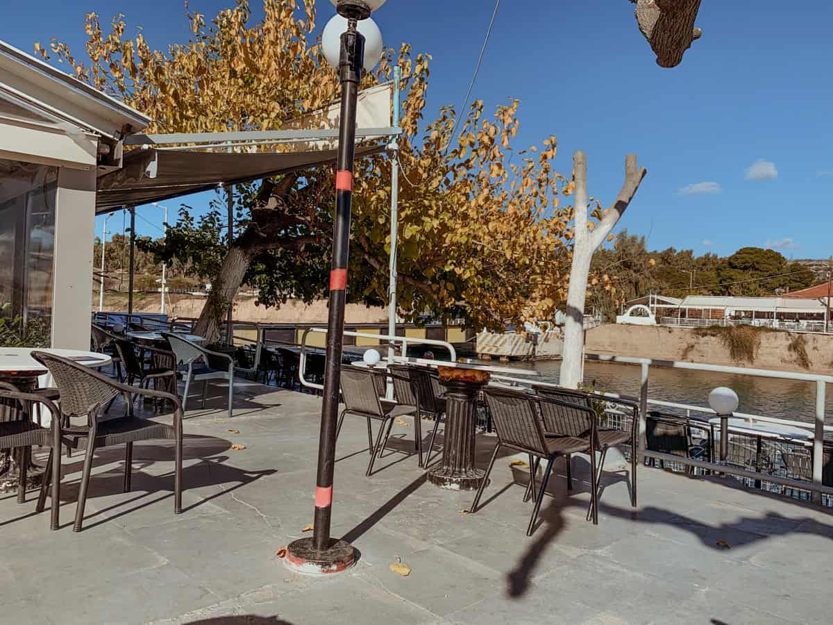 Isthmia Bridge Café overlooking a calm waterway and a distant riverside view.