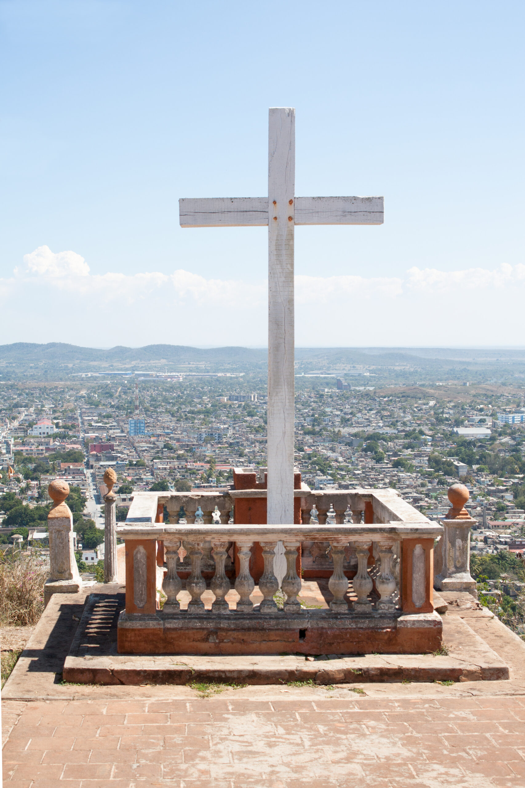 A large wooden cross stands on a viewing platform at Loma de la Cruz, overlooking Holguín, Cuba.